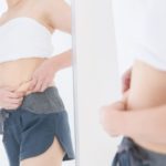 お腹をつまむ女性